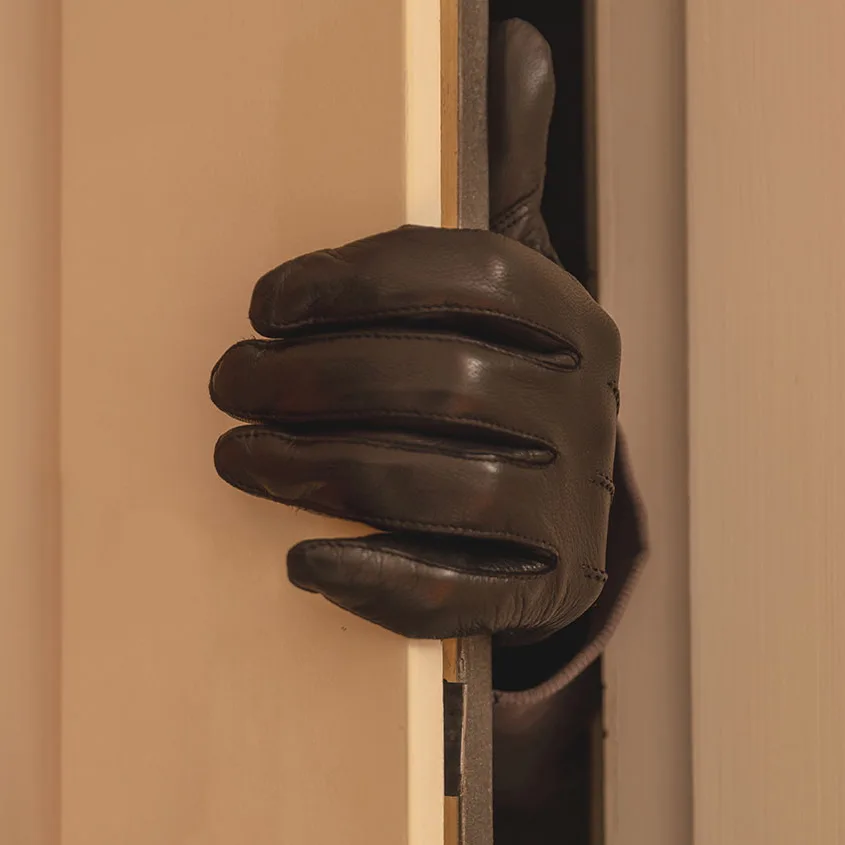 Einbrecher tritt durch die Tür ins Haus